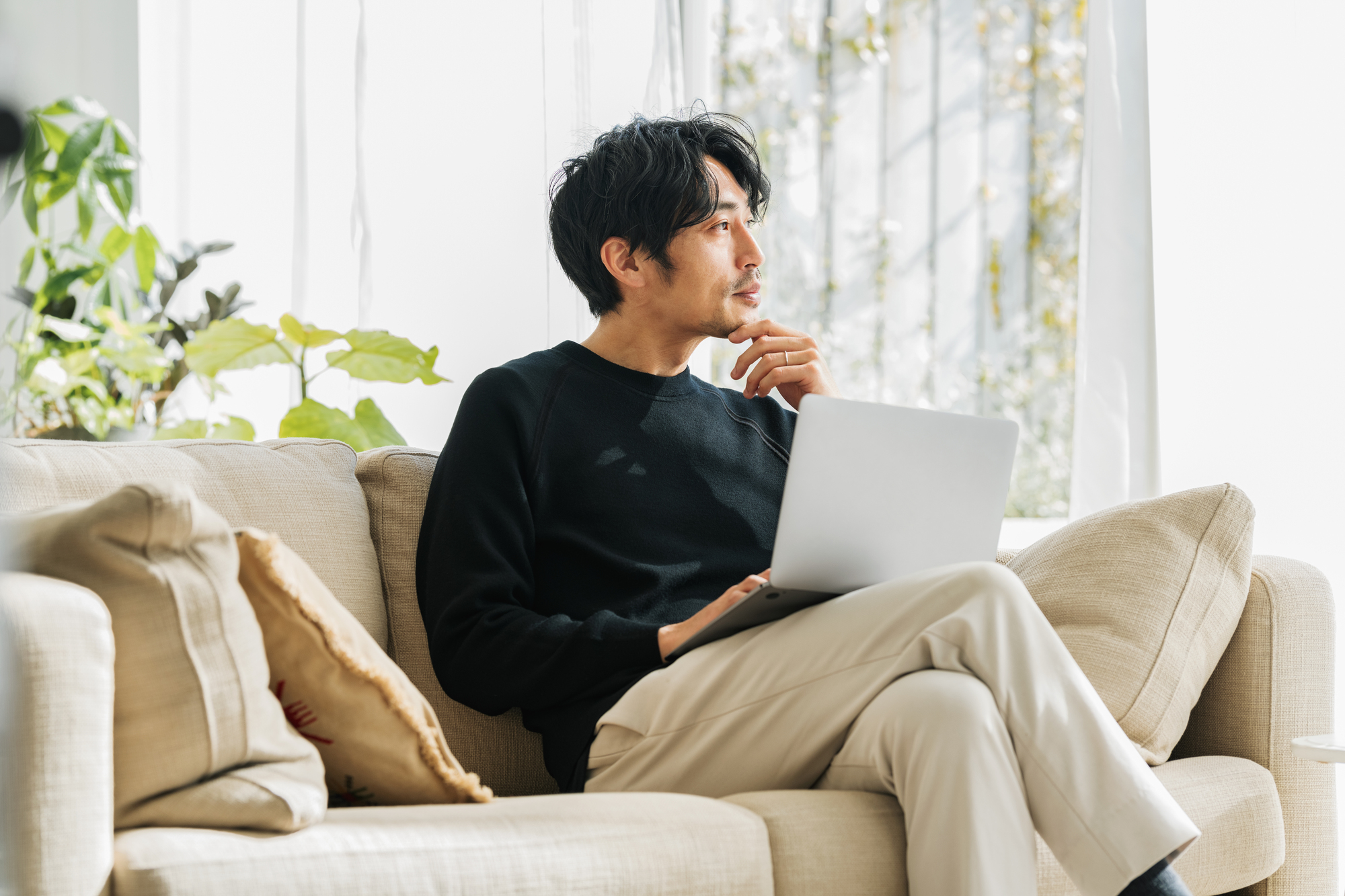 自宅のソファーでテレワークするミドル男性